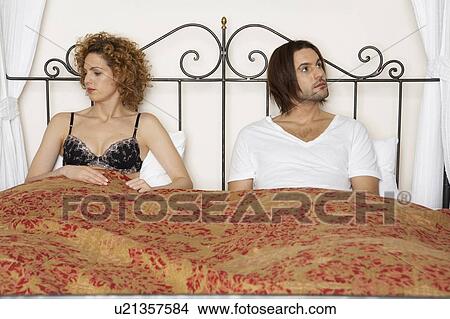 young couple sitting in bed wearing underwear looking away from each other View Large Photo Image Picture - young couple sitting in bed wearing underwear looking away from each other. Fotosearch