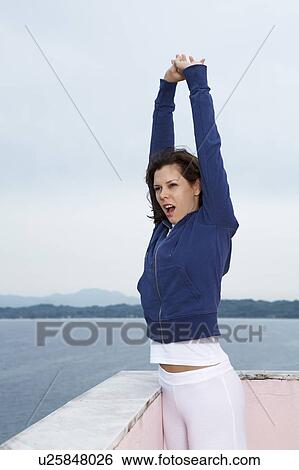 Young woman on balcony yawning and stretching morning sea and sky in background. View Large Photo Image Stock Photograph - Young woman on balcony yawning and stretching morning sea and sky in background.. Fotosearch