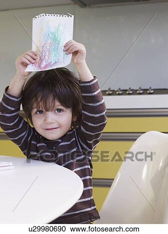 Stock Image - Boy holding up drawing. Fotosearch