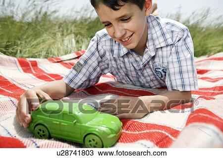 Stock Image - Boy playing with green toy car. Fotosearch