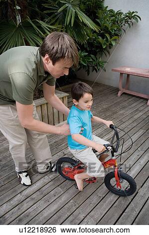 Stock Photograph - Boy riding a bike with father.. Fotosearch