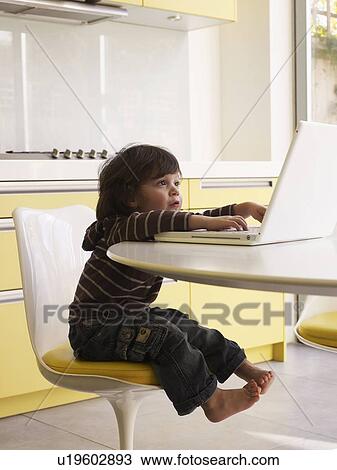Boy using laptop in kitchen View Large Photo Image Stock Image - Boy using laptop in kitchen. Fotosearch