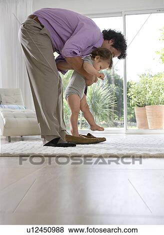 Father puts baby in shoes at home View Large Photo Image Stock Photo - Father puts baby in shoes at home. Fotosearch