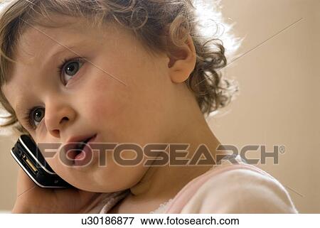 Stock Photo - Girl (9-12 months) using mobile phone. Fotosearch