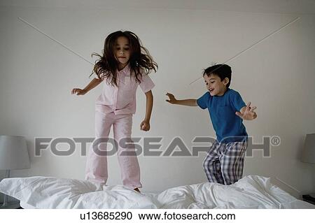 Girl and boy jumping on a bed. View Large Photo Image Stock Image - Girl and boy jumping on a bed.. Fotosearch