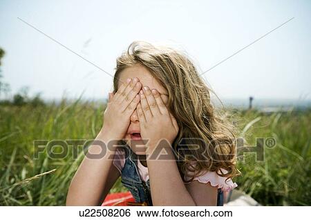 Stock Photograph - Girl hiding behind hands. Fotosearch