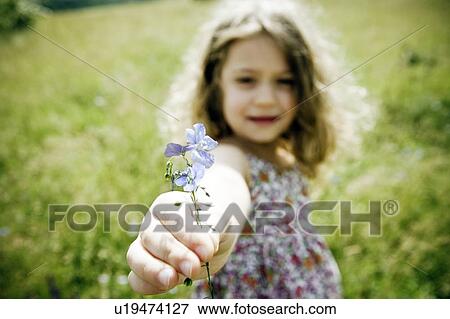Stock Photo - Girl holding flower to camera. Fotosearch