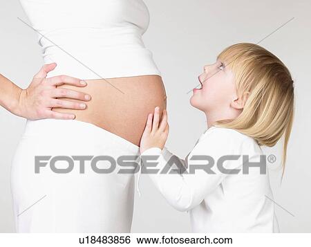 Stock Photograph - Girl holding her mother's pregnant belly. Fotosearch
