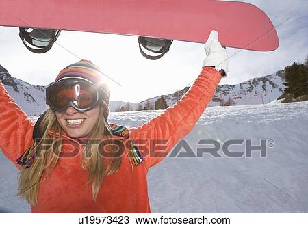 Girl lifting ski board, smiling View Large Photo Image Stock Image - Girl lifting ski board, smiling. Fotosearch