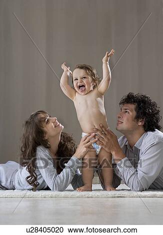 Parents helping baby to stand up View Large Photo Image Stock Image - Parents helping baby to stand up. Fotosearch