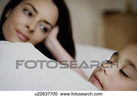 Stock Image - Portrait of mother and daughter in bed.. Fotosearch