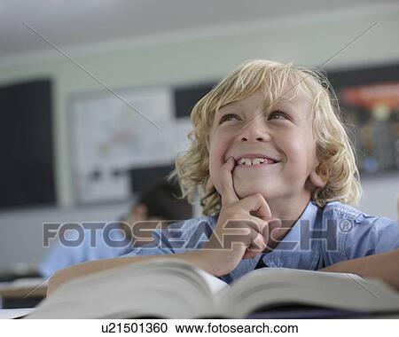 Stock Image - School boy thinking in class. Fotosearch