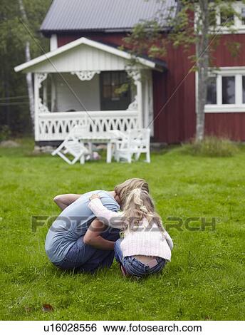 Stock Photograph - Woman with young girl crouched down in yard.. Fotosearch