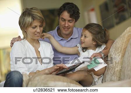 Stock Image - Young family on sofa budgeting. Fotosearch