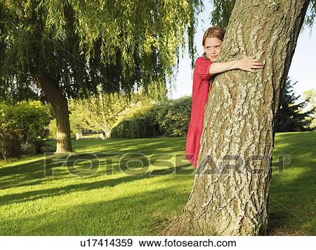 Stock Photo - Young girl hugging tree. Fotosearch