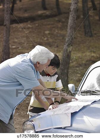 Boy (8-10) and grandfather leaning on car bonnet, looking at road map View Large Photo Image Stock Photography - Boy (8-10) and grandfather leaning on car bonnet, looking at road map. Fotosearch