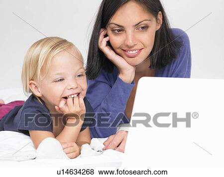 Daughter and mother looking at a laptop View Large Photo Image Stock Photo - Daughter and mother looking at a laptop. Fotosearch