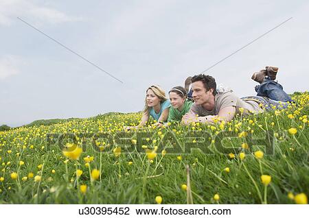 Stock Image - Family laying in field. Fotosearch