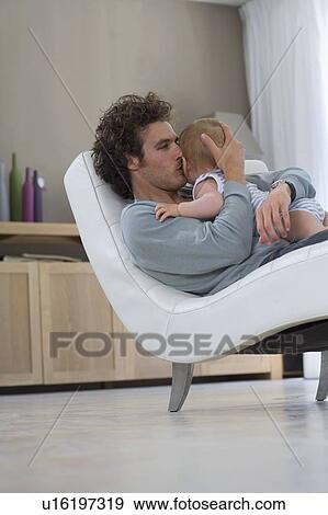 Father kisses baby, sits in chair View Large Photo Image Stock Photo - Father kisses baby, sits in chair. Fotosearch