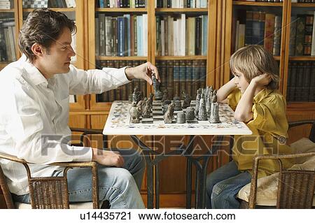 Stock Image - Father playing chess with young boy. Fotosearch