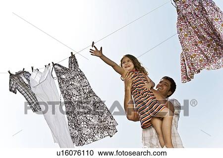 Stock Image - Man lifting girl up to washing line. Fotosearch