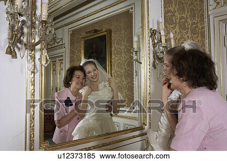Stock Photography - Mother and bride looking at reflection in mirror. Fotosearch