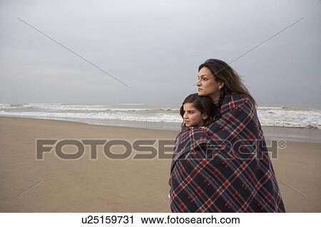 Mother and daughter (9-11) wrapped in blanket on beach View Large Photo Image Stock Image - Mother and daughter (9-11) wrapped in blanket on beach. Fotosearch