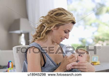 Stock Photo - Mother bottle feeds baby. Fotosearch