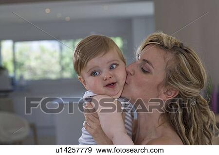 Mother kisses her baby at home View Large Photo Image Stock Photo - Mother kisses her baby at home. Fotosearch
