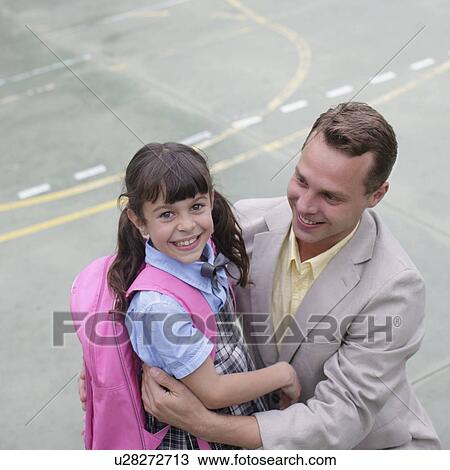 Stock Image - School girl hugging father. Fotosearch