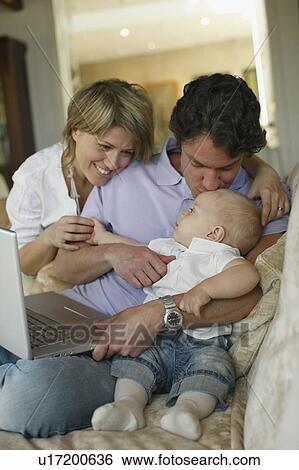 Stock Photograph - Young family on sofa with laptop. Fotosearch
