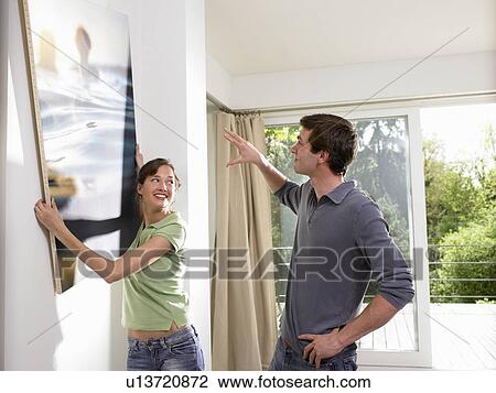 Stock Image - Couple hanging a painting. Fotosearch