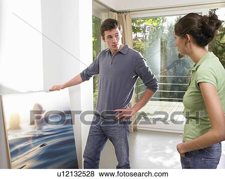 Couple hanging a painting View Large Photo Image Stock Photo - Couple hanging a painting. Fotosearch