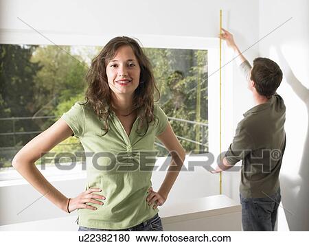 Stock Image - Couple taking measurement of their home. Fotosearch