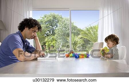Father and baby reading at table View Large Photo Image Stock Photo - Father and baby reading at table. Fotosearch