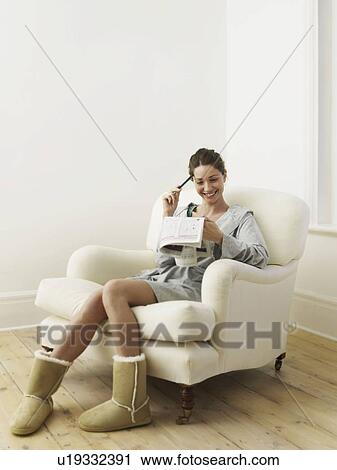 Stock Image - Woman doing puzzle in newspaper. Fotosearch
