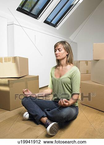 Stock Image - Woman doing yoga with moving boxes around her.. Fotosearch