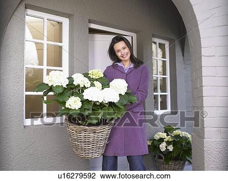 Stock Image - Woman holding flowers on the patio. Fotosearch