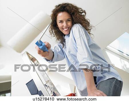 Stock Image - Woman painting a wall. Fotosearch