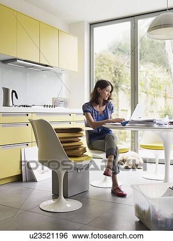 Stock Photograph - Woman running business at kitchen table. Fotosearch