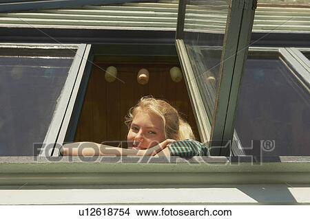 Picture - Young woman appearing from window.. Fotosearch