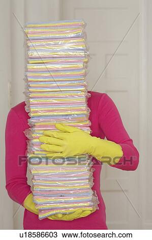 Stock Image - Young woman carrying stack of cleaning cloths. Fotosearch