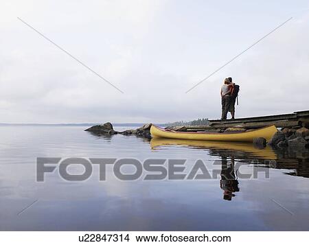 Picture - Couple embracing on a dock near a boat.. Fotosearch