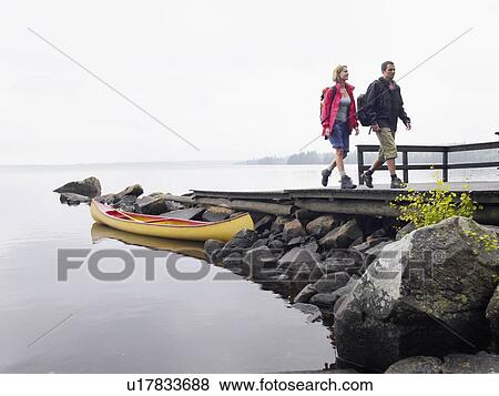 Stock Photo - Couple walking on dock near a boat.. Fotosearch