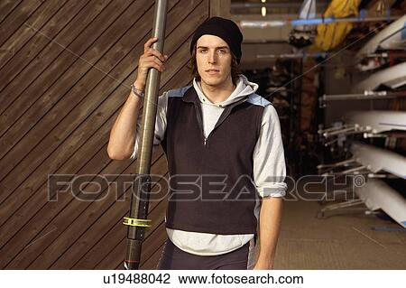 Stock Image - Oarsman outside boat shed.. Fotosearch