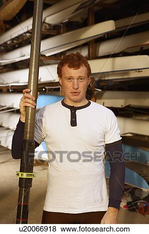 Stock Photo - Oarsman outside boat shed.. Fotosearch