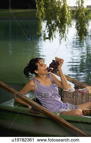 Stock Image - Woman having a picnic on boat. Fotosearch