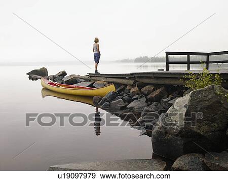 Woman standing on a dock near a boat. View Large Photo Image Stock Photo - Woman standing on a dock near a boat.. Fotosearch