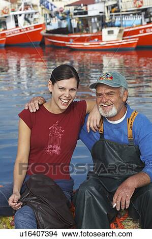 Young girl and fisherman sitting together on fishing nets laughing fishing boats in background. View Large Photo Image Picture - Young girl and fisherman sitting together on fishing nets laughing fishing boats in background.. Fotosearch