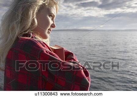Young Woman By sea cuddling book. View Large Photo Image Stock Image - Young Woman By sea cuddling book.. Fotosearch